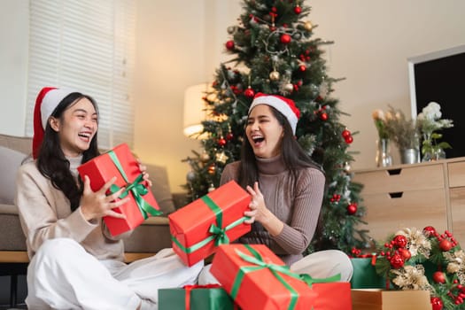 Happy lesbian couple enjoying a festive Christmas celebration at home, surrounded by gifts and holiday decorations.