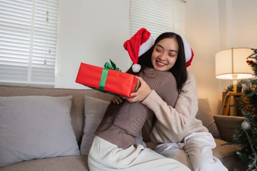 Happy lesbian couple enjoying a Christmas celebration at home, exchanging gifts and sharing festive joy.