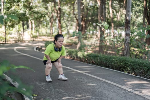 A tired woman pauses during her jog in a vibrant park, capturing the essence of determination and perseverance.