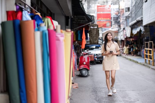 A young woman walks confidently through the city, showcasing a modern urban lifestyle with her smartphone and trendy outfit.