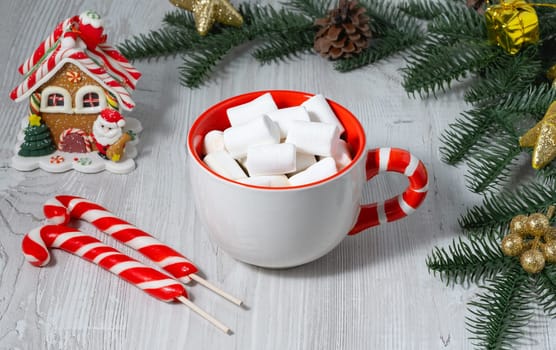 Festive cup with lollipop handle with coffee and marshmallows on wooden table in cozy setting.