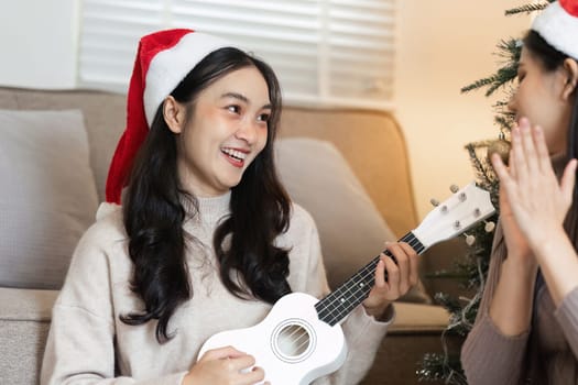 Two young women enjoying music and celebrating Christmas with joy and laughter in a cozy home environment.