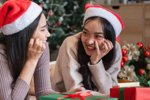 Happy lesbian couple enjoying a Christmas celebration with gifts and holiday decorations in a cozy home environment.