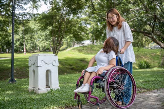 A joyful scene of friendship as a young woman in a wheelchair and her friend enjoy a sunny walk in the park.