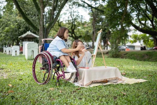 Two young women, one in a wheelchair, drawing together in a park, showcasing friendship, creativity, and inclusivity.