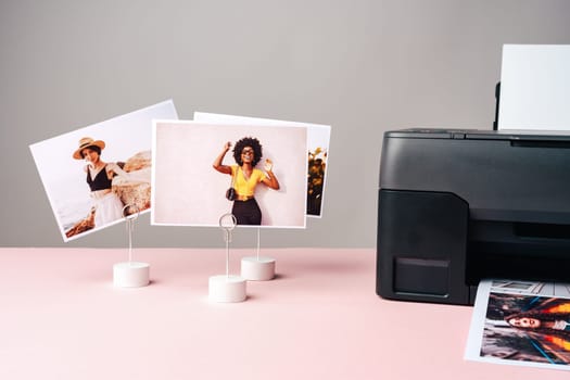 Modern laser printer printing color photos of women close up on desk