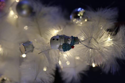 A delightful and charming snowman ornament is hanging beautifully on a whimsical white Christmas tree, adding cheer