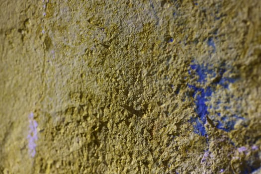 This is a closeup of a beautifully textured yellow wall that features subtle blue accents with rough details