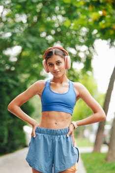 A fit young woman in stylish sportswear and headphones enjoys outdoor fitness in a vibrant atmosphere