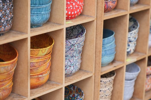 A vibrant collection of handcrafted bowls arranged on a rustic shelf for optimal display