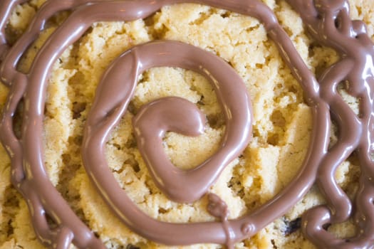 A sweet cookie topped with chocolate drizzle, served beautifully on a sleek black plate