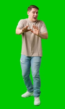 Man expressing fear while standing against a bright green background in studio
