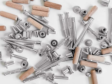Assorted hardware pieces. Screws, dowels, and fasteners on white background.