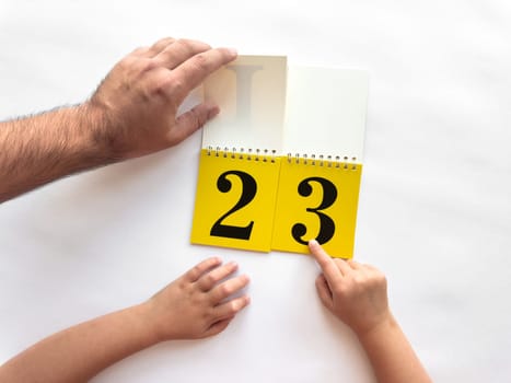 Learning numbers together. Adult and child hands interacting with calendar pages.