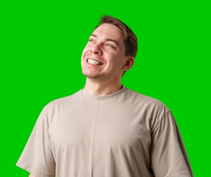 Smiling man in a beige shirt poses against a bright green background in studio