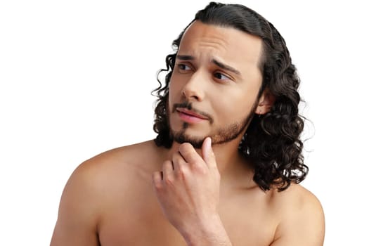 Young man with curly hair thoughtfully posing against a plain background in a studio setting
