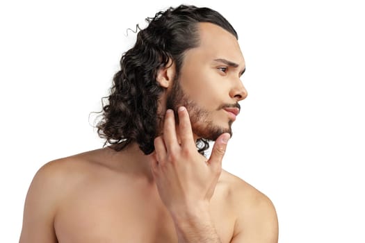 Young man with curly hair thoughtfully posing against a plain background in a studio setting