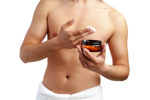 A young man applying skincare cream on his face with a focused expression, demonstrating personal grooming at home close up