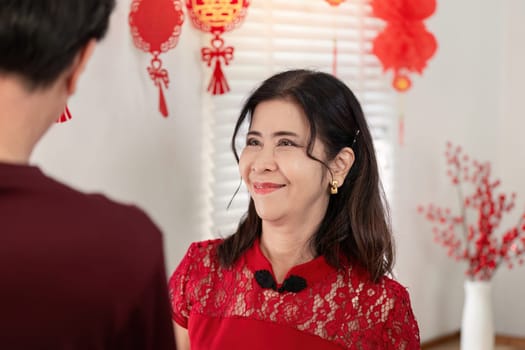 An elderly couple shares happiness and traditions during Chinese New Year surrounded by festive decorations and love.