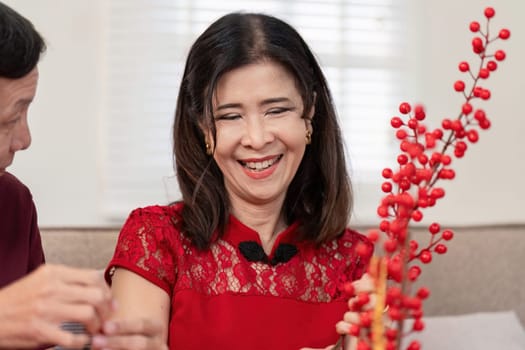 An elderly couple joyfully participates in Chinese New Year festivities surrounded by rich traditions and vibrant decorations.