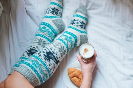 A young beautiful woman in warm handmade knitted clothes at home. . spring, winter season. Gaiters. Knee socks. Leggings.