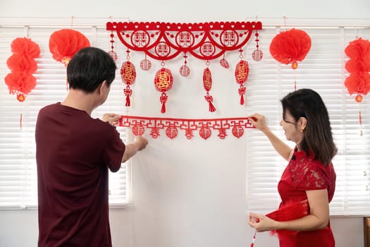 An elderly couple joyfully decorates their home for Chinese New Year showcasing traditions and family togetherness.
