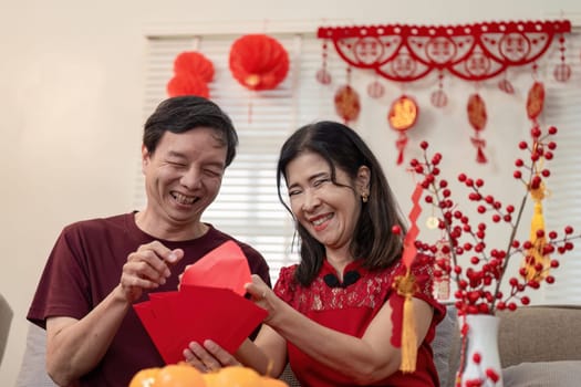 An elderly couple joyfully celebrates Chinese New Year at home surrounded by colorful decorations and shared happiness.