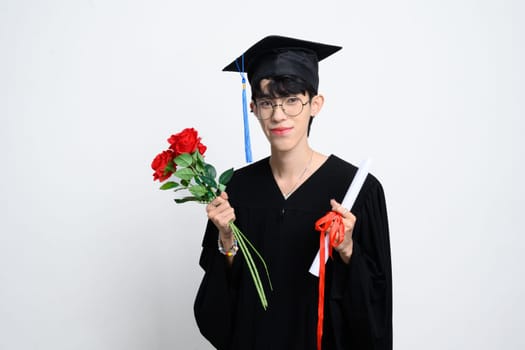 Proud graduate holding a bouquet and diploma standing on white background. Academic achievement concept.