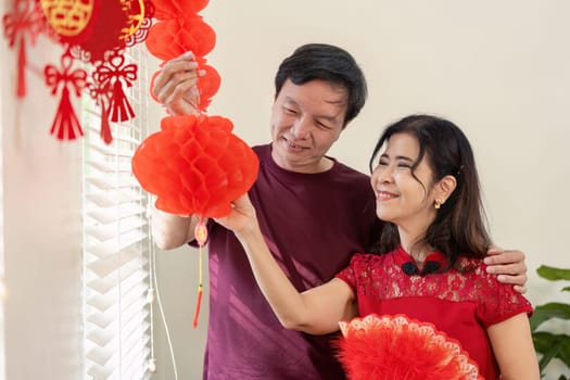 A joyful elderly couple decorates their home for Chinese New Year embracing traditions and sharing moments of happiness.