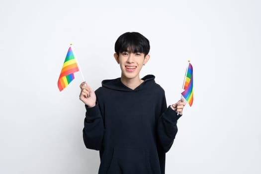 Cheerful man wearing black hoodie holding up rainbow pride flags. Unity and celebration of LGBTQ rights concept.