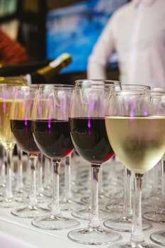 A beautifully arranged collection of wine glasses filled with red and white wines, set on a white tablecloth. The image captures an elegant scene perfect for events such as parties, weddings, or wine tastings