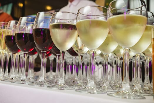 A beautifully arranged collection of wine glasses filled with red and white wines, set on a white tablecloth. The image captures an elegant scene perfect for events such as parties, weddings, or wine tastings