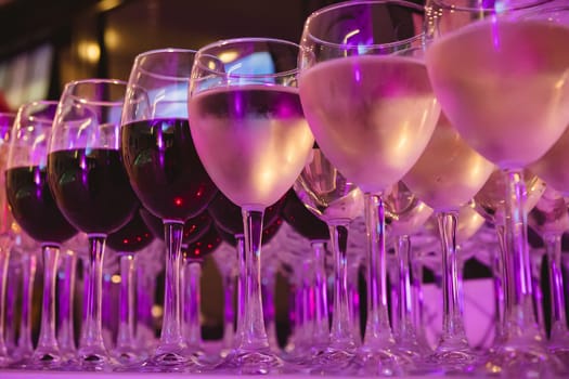 A beautifully arranged collection of wine glasses filled with red and white wines, set on a white tablecloth. The image captures an elegant scene perfect for events such as parties, weddings, or wine tastings