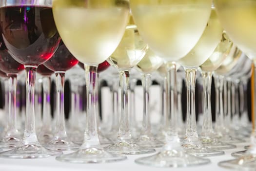 A beautifully arranged collection of wine glasses filled with red and white wines, set on a white tablecloth. The image captures an elegant scene perfect for events such as parties, weddings, or wine tastings