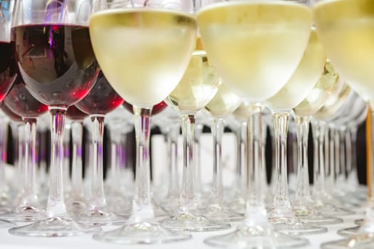 A beautifully arranged collection of wine glasses filled with red and white wines, set on a white tablecloth. The image captures an elegant scene perfect for events such as parties, weddings, or wine tastings