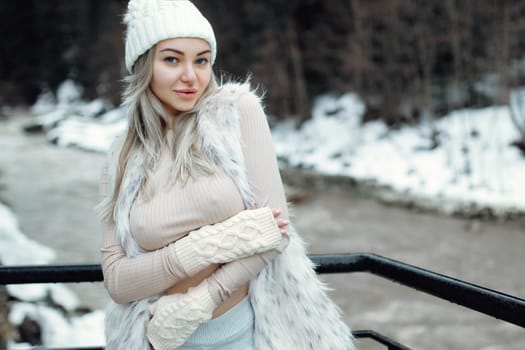 Portrait of a sexy girl in a fur vest and a fluffy hat in the winter season. Beautiful sexy breasts visible through t-shirt.