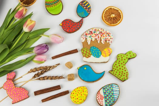 Tulips and gingerbread cookies on white background for Easter.
