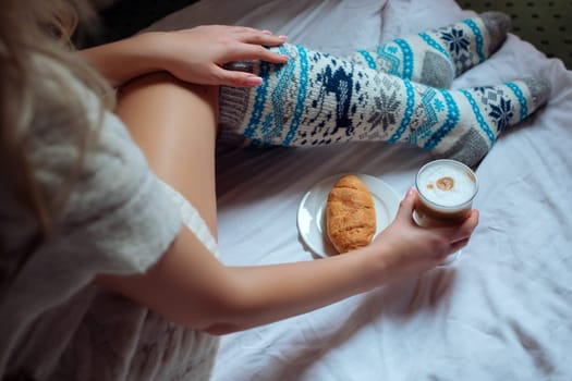 A young beautiful woman in warm handmade knitted clothes at home. . spring, winter season. Gaiters. Knee socks. Leggings.