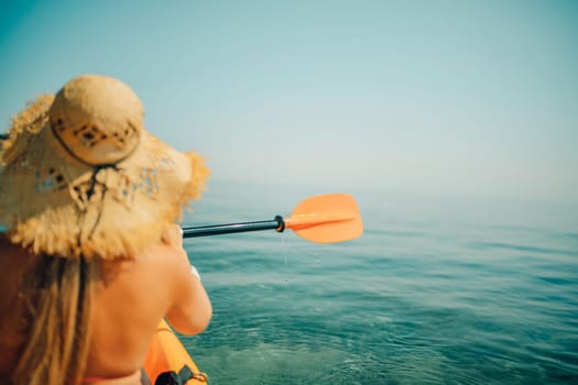 Woman in kayak back view. Happy woman with long hair in a swimsuit and hat floating in kayak on the sea. Summer holiday vacation. Summer holidays vacation at sea