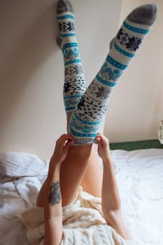 A young beautiful woman in warm handmade knitted clothes at home. . Autumn, Gaiters. Knee socks. Leggings.
