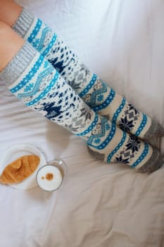 A young beautiful woman in warm handmade knitted clothes at home. . spring, winter season. Gaiters. Knee socks. Leggings.