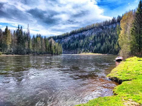 A tranquil river winds through vibrant trees under a dramatic sky.