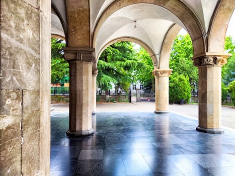 Stone arches frame a peaceful outdoor area, highlighting lush greenery and a serene atmosphere, inviting visitors to relax and explore.