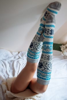 A young beautiful woman in warm handmade knitted clothes at home. . Autumn, Gaiters. Knee socks. Leggings.