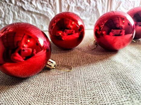 Bright red ornaments are scattered across a soft fabric, creating a warm, festive vibe while reflecting the surroundings.
