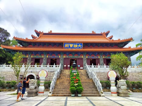 Hong Kong - April 08, 2024: Visitors admire the colorful architecture of Po Lin Buddhist Monastery nestled in the tranquil Ngong Ping Village, Hong Kong.