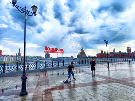 Yoshkar-Ola, Russia - July 04, 2024: Visitors enjoy the vibrant atmosphere at Bryggen Embankment in Yoshkar-Ola, surrounded by beautiful architecture and dynamic skies.