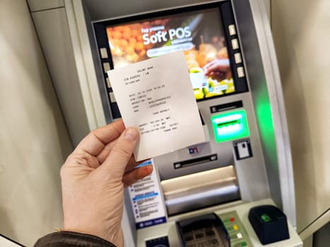 Ulaanbaatar, Mongolia - October 20, 2024: Person holds a receipt after a transaction at an ATM in Ulaanbaatar, showcasing city life and banking services.