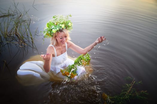 Girl in White Sundress With Flower Wreath in Water at Sunset Celebrating Ivan Kupala Holiday