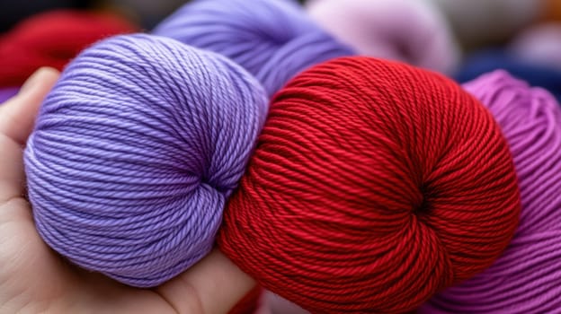 A close-up of vibrant red and purple yarn balls held in a hand, highlighting their texture and color. Perfect for knitting, crochet, and textile projects, emphasizing creativity and craftsmanship
